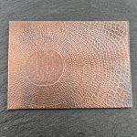 Textured copper sheet on dark surface.