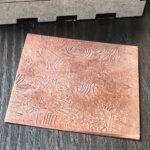 Copper sheet with abstract engraved patterns.