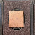 Ornate copper plate on textured brown background.