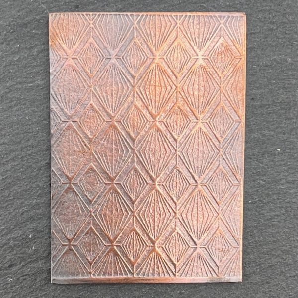 Textured copper plate with geometric pattern.