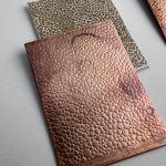 Textured copper and metallic sheets on table.