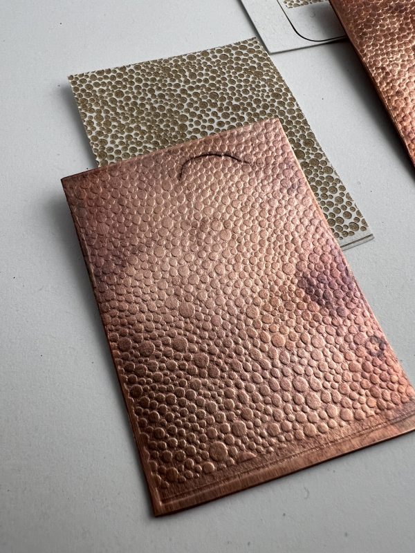 Textured copper and metallic sheets on table.