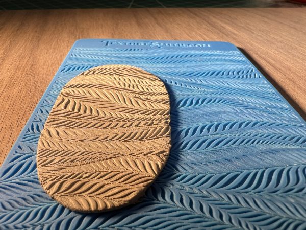 Clay on patterned blue silicone mold.