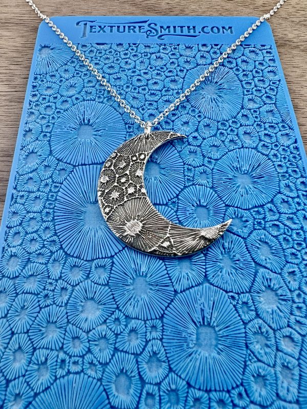 Silver crescent moon necklace on blue background.
