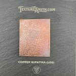 Copper with patina sample on textured background.