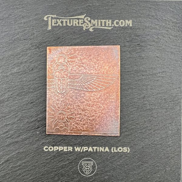 Copper with patina sample on textured background.