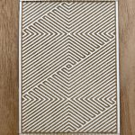 Geometric pattern laser-cut stencil on wood.