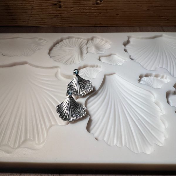 Silver earrings on shell-shaped silicone mold.