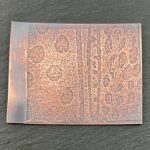 Patterned copper plate with textured surface design.
