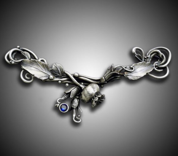 Intricate silver brooch with leaf design.