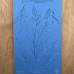 Blue textured botanical stencil on wood surface.