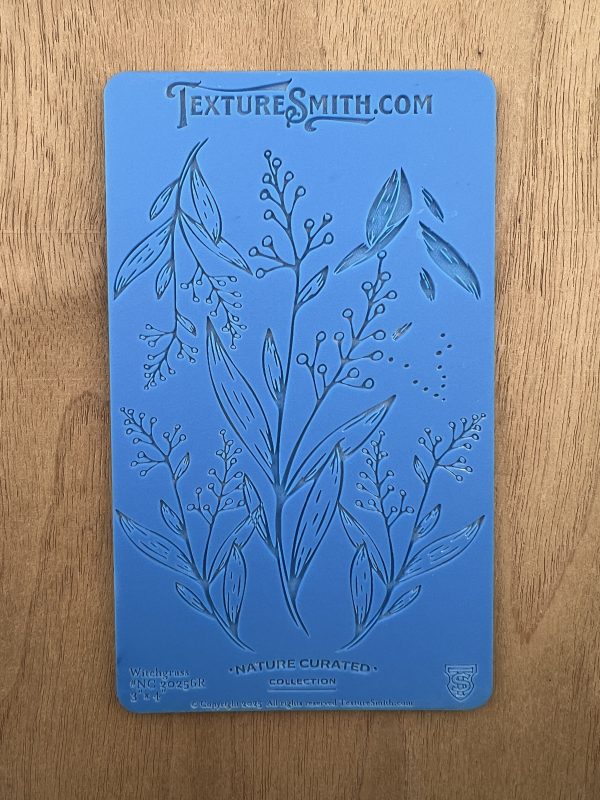Blue textured botanical stencil on wood surface.