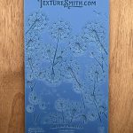 Blue dandelion-patterned texture sheet on wood.
