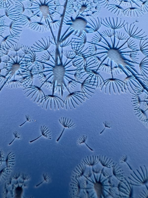 Blue embossed dandelion pattern on surface.