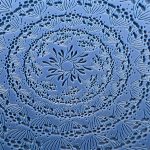 Intricate floral mandala pattern on blue background.