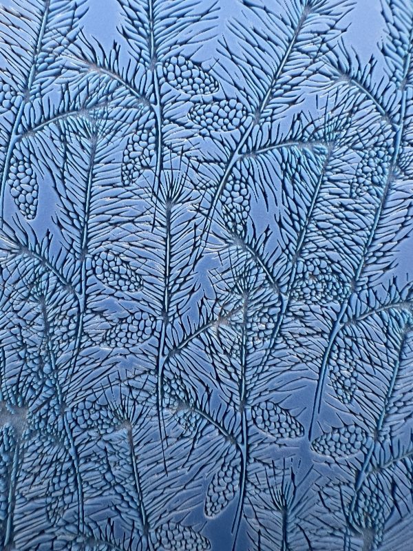 Frost patterns resembling pine branches on glass.