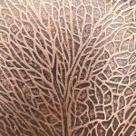 Intricate leaf-patterned texture on brown surface.