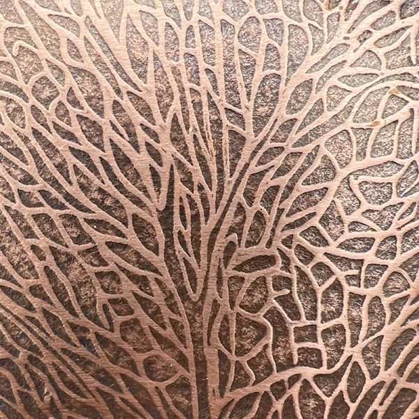 Intricate leaf-patterned texture on brown surface.