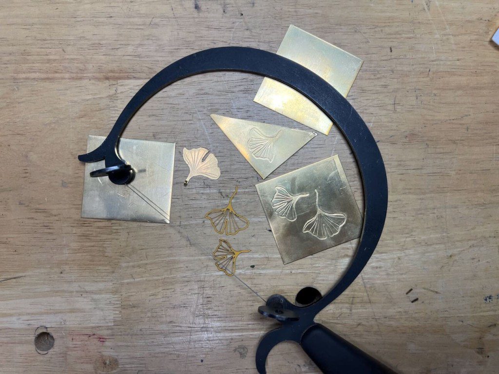 Black curved tool on a wooden surface with paper scraps.