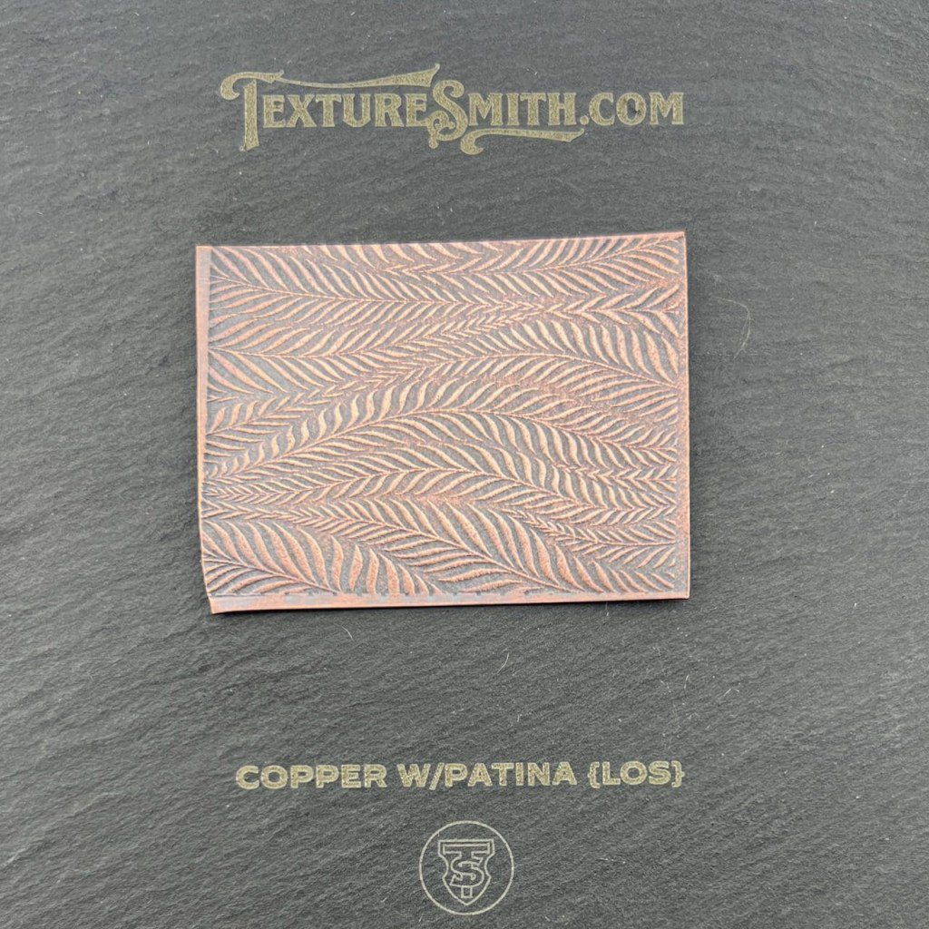 Copper sheet with intricate wapatui pattern on a dark surface.