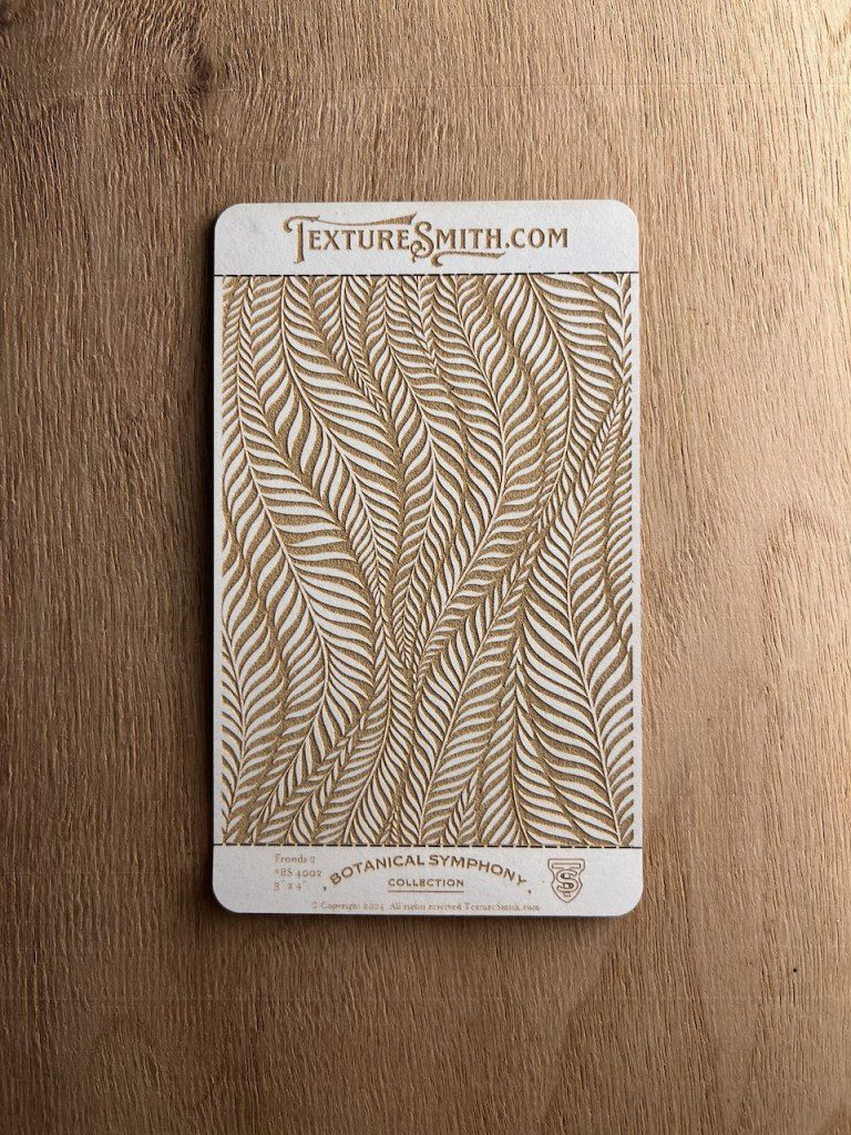 Decorative wallpaper sample with a gold leaf pattern on a beige background.