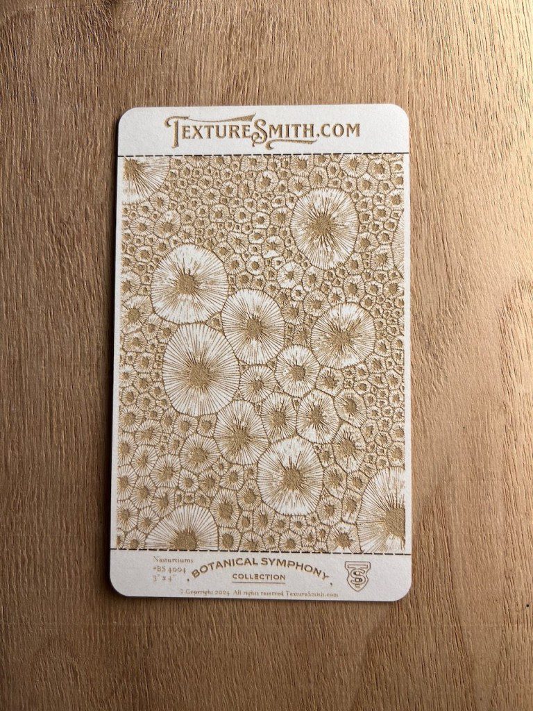 A textured sample card with circular, lace-like patterns on a beige background.