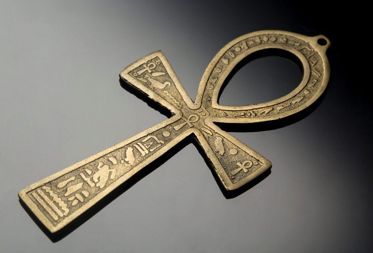 Golden Ankh symbol with detailed hieroglyphics on a dark surface.