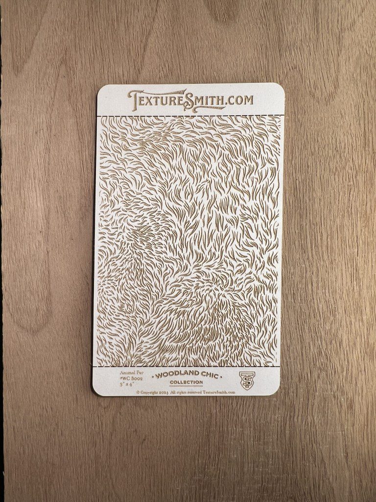 Intricate floral and leaf pattern engraved on a rectangular metal plate.