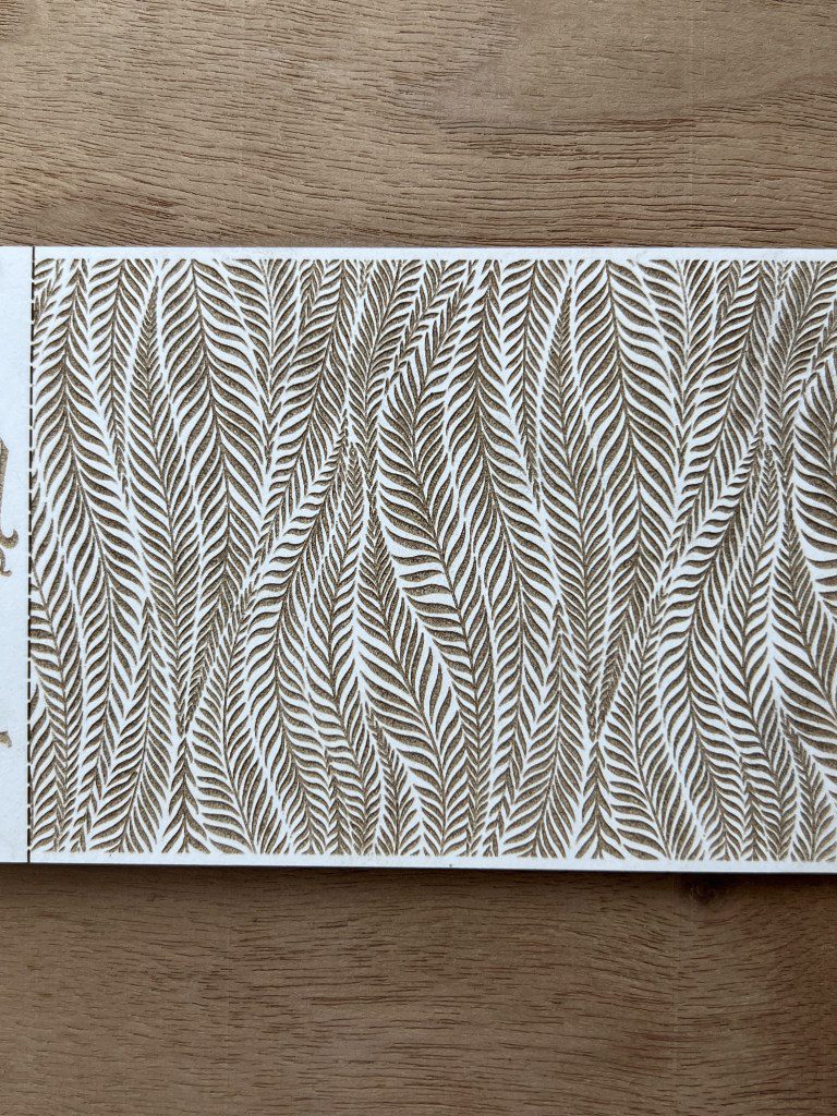 Brown and white fabric with a leafy fern pattern and ruler for scale.