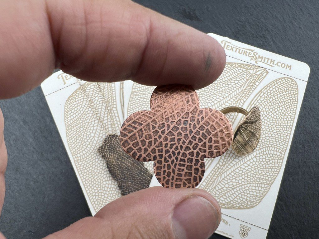 A hand holding a small, patterned leaf with a unique texture.