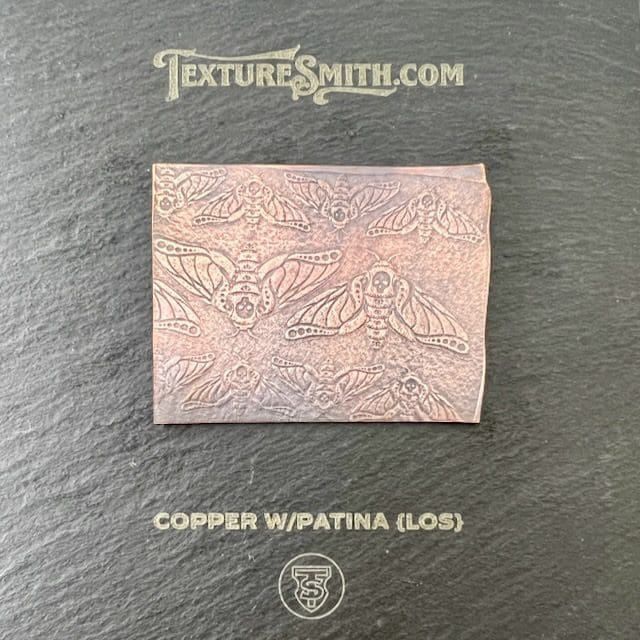 A copper sheet with a patina finish showing intricate patterns.
