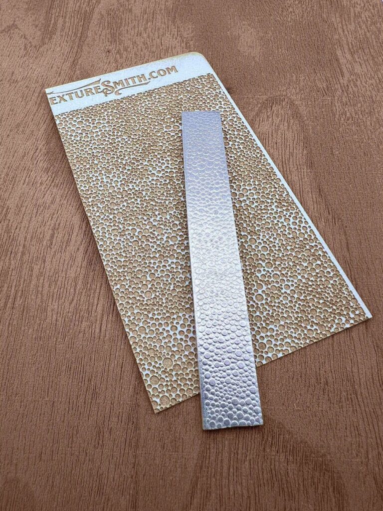 A metallic textured bookmark on a speckled, golden background.