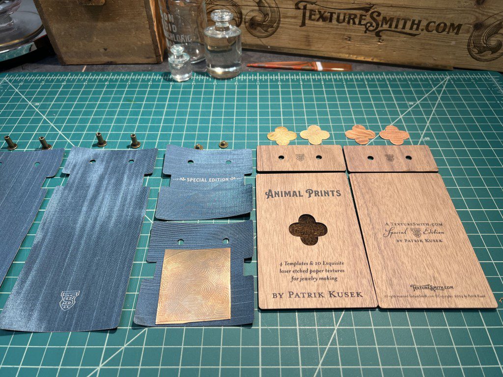 Laser-cut wooden pieces and a metal part on a green cutting mat.