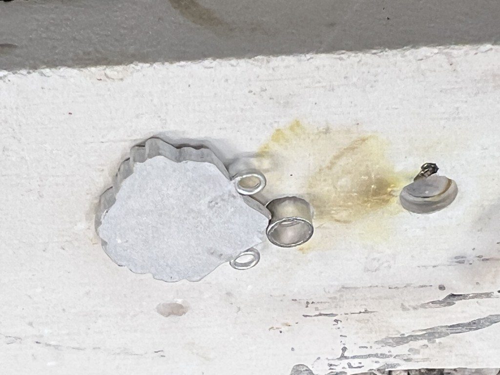 Old paint and rust damage on a metal surface with screws.