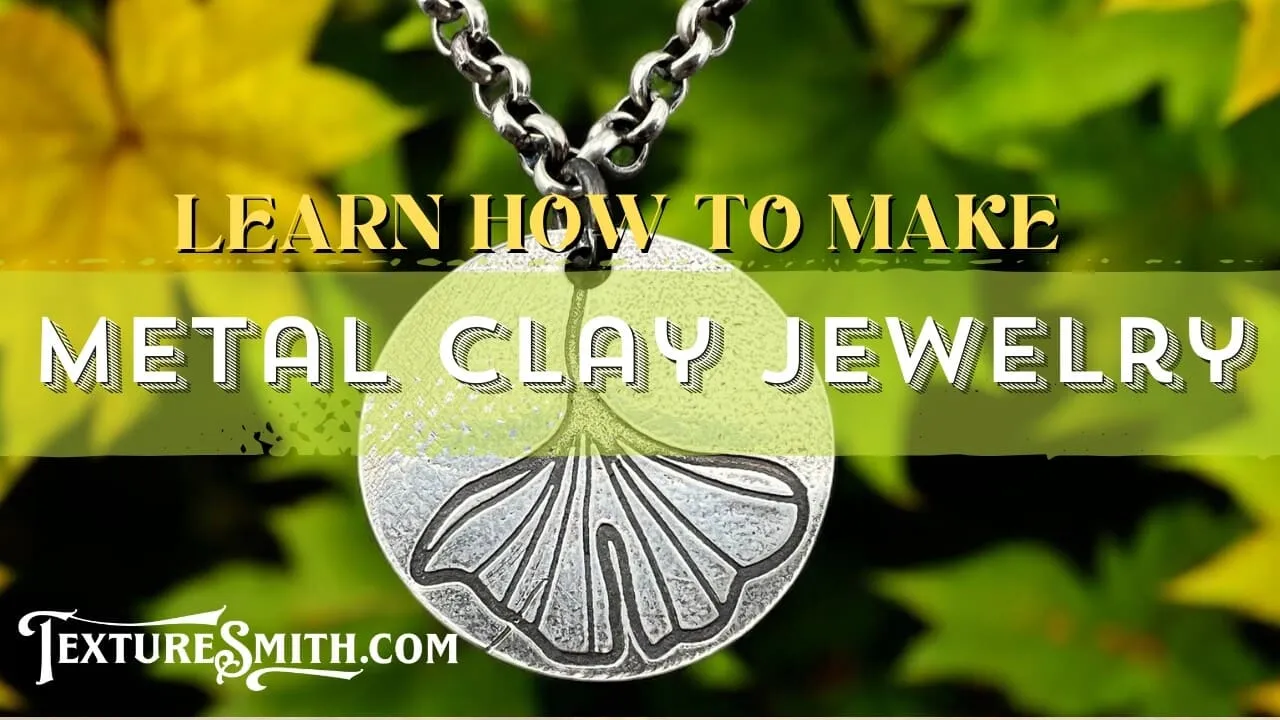 Close-up of silver clay jewelry pendant with leaf design on chain.
