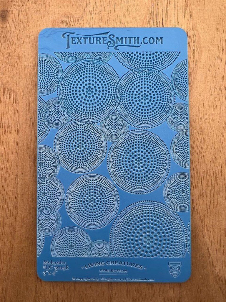 Blue stencil sheet with circular geometric patterns for art and crafts.