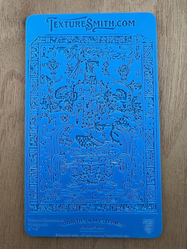 Blue embossed card with intricate floral and heart patterns.