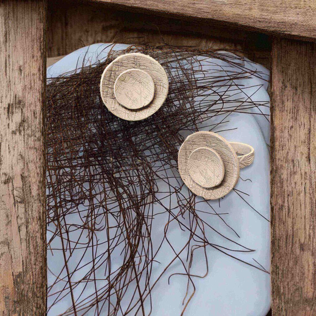 Two woven straw hats hanging on a wooden frame with branches behind.