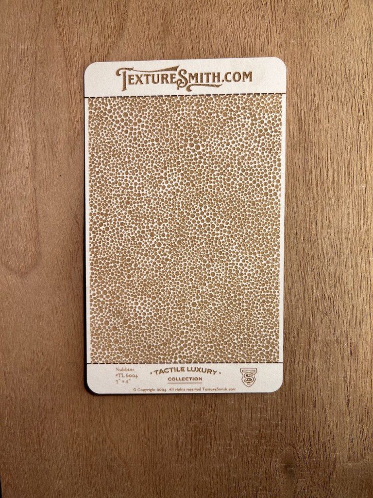 Close-up of a textured, speckled surface sample on a card.