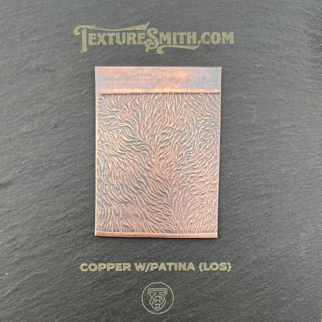 A copper sheet with intricate patina texture on a black background.