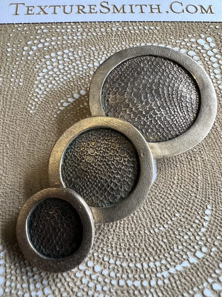 Three metal rings of different sizes placed on a textured surface.