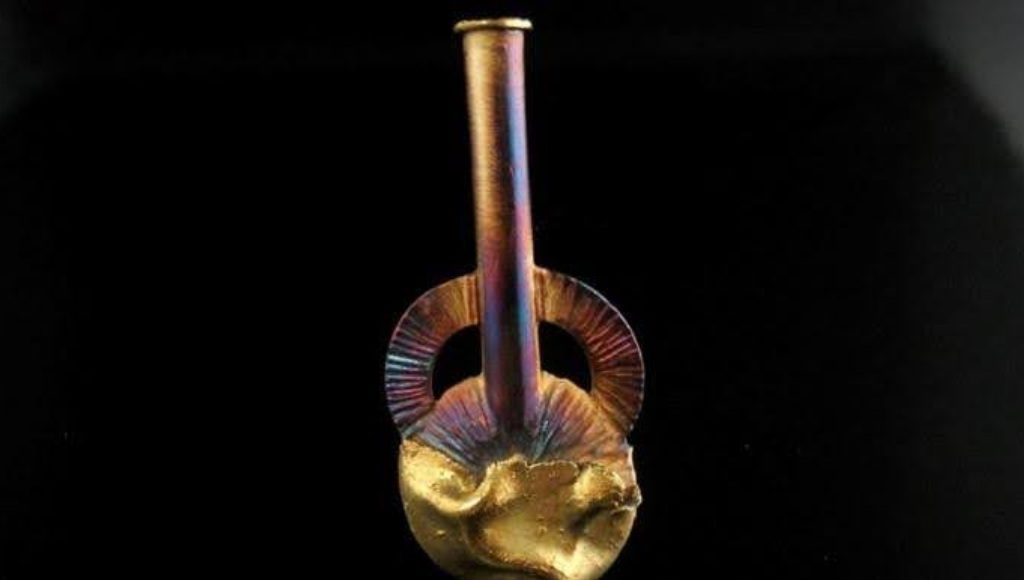 Close-up of a unique, artistic glass pipe with a dark background.