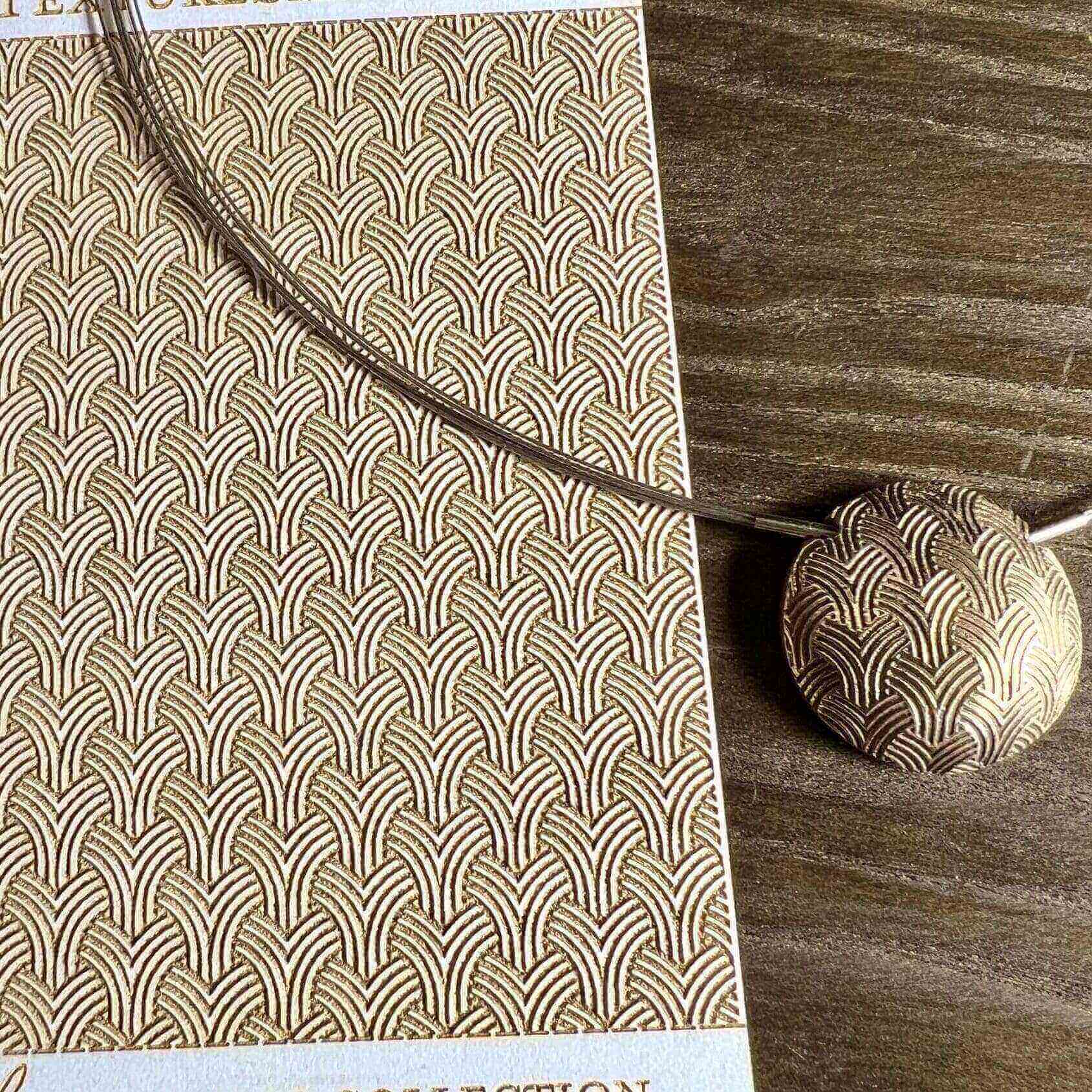 A textured notebook with a cord and round pendant on a wooden surface.