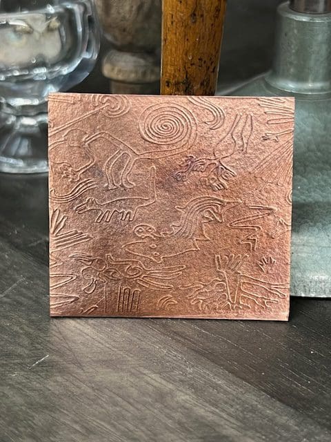 A brown leather wallet with an embossed floral pattern.