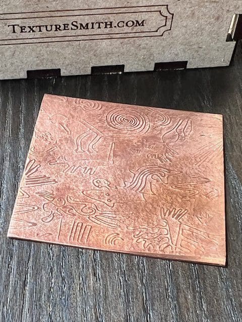 A rectangular tile with a textured, swirled pattern on a dark surface.