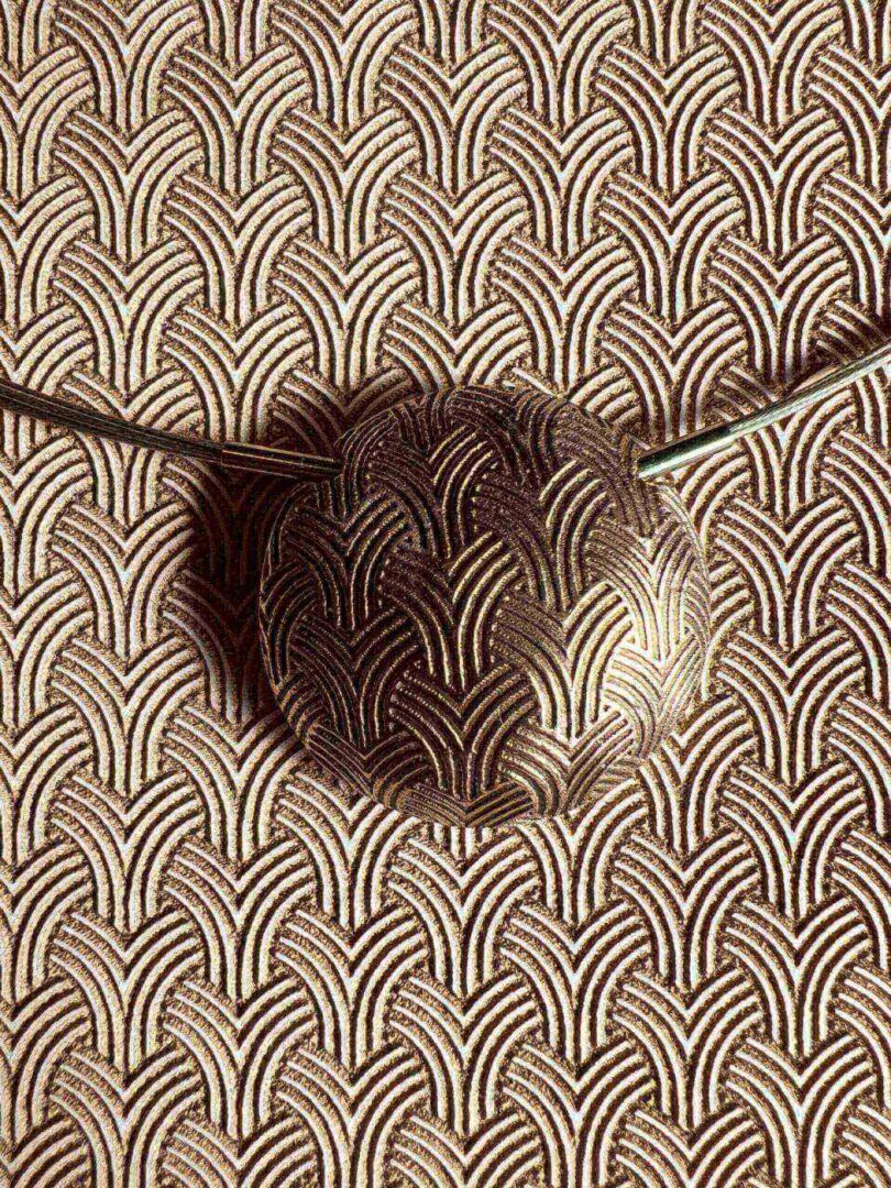 An artistic metal ladle with a patterned background.