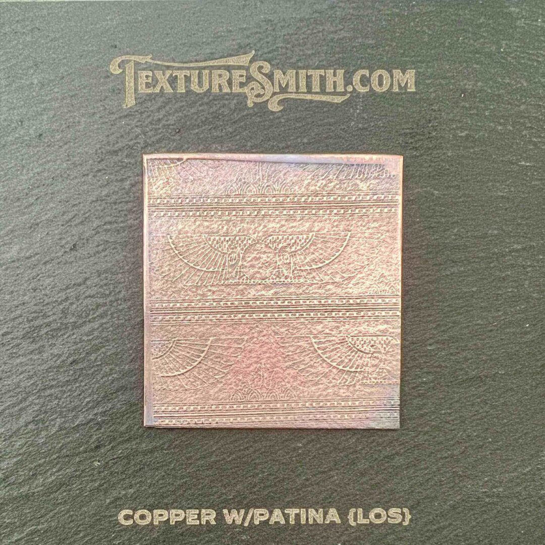 Copper square with patina and oxidation marks on a neutral background.