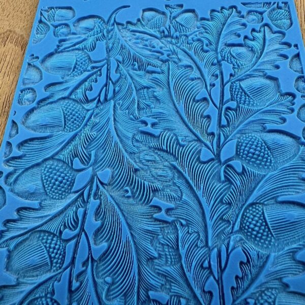 Detailed blue fabric with intricate leaf and floral patterns.