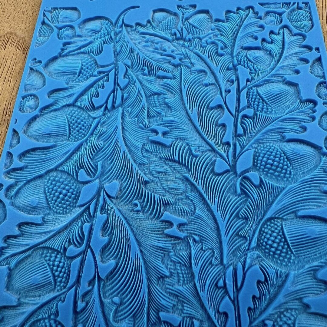 Detailed blue fabric with intricate leaf and floral patterns.