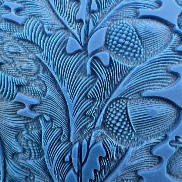 Intricate blue embossed floral and pinecone pattern on a textured surface.